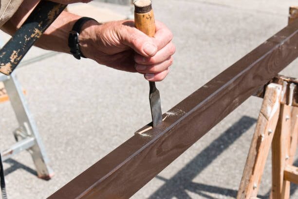 A man is using a chisel on a wood