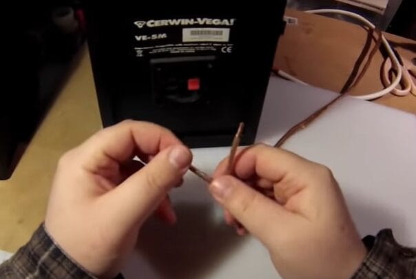 A person is learning how to strip speaker wire and expertly placing them into a black box