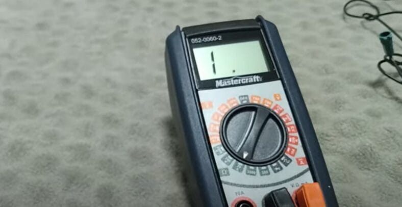 A multimeter on a table next to a wire for testing Christmas lights