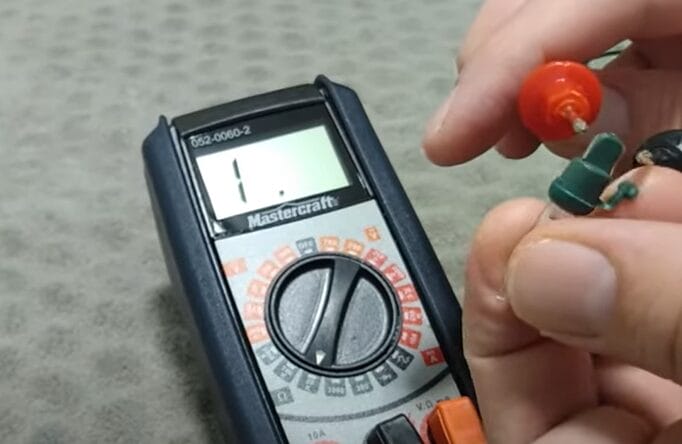 A person is using a multimeter to test Christmas lights
