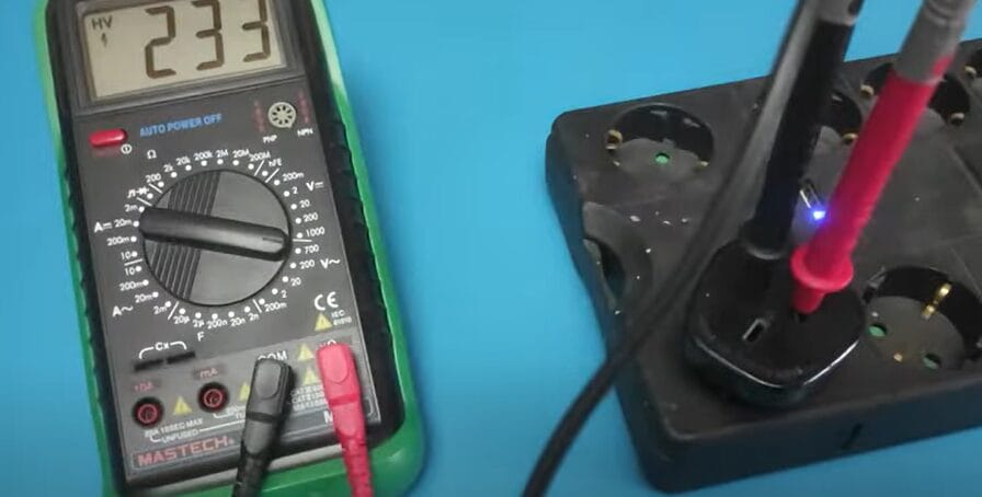 A multimeter is connected to a power supply to check 240 voltage.