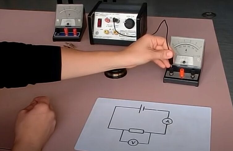 A person is drawing a diagram of an ammeter connected to a circuit on a piece of paper