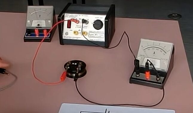 A person is using an electronic device on a table to learn how an ammeter is connected to a circuit
