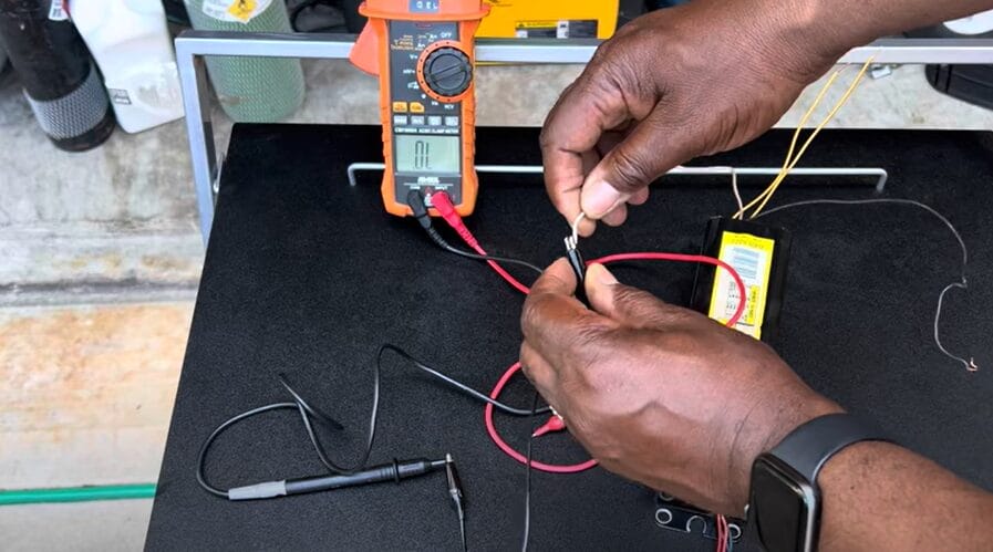 A man demonstrating how to test a ballast using a multimeter on a table