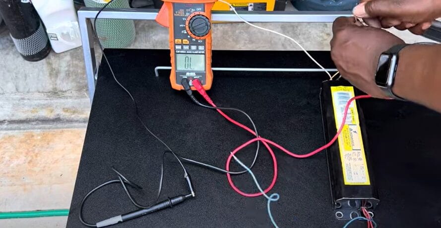 A person is using a multimeter to test a ballast