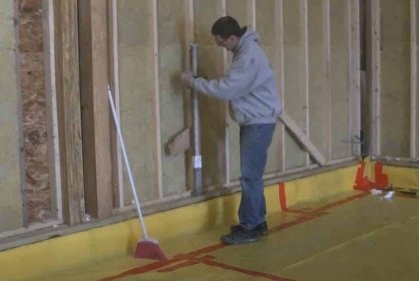 A man holding a pole while learning how to use a laser level for grading