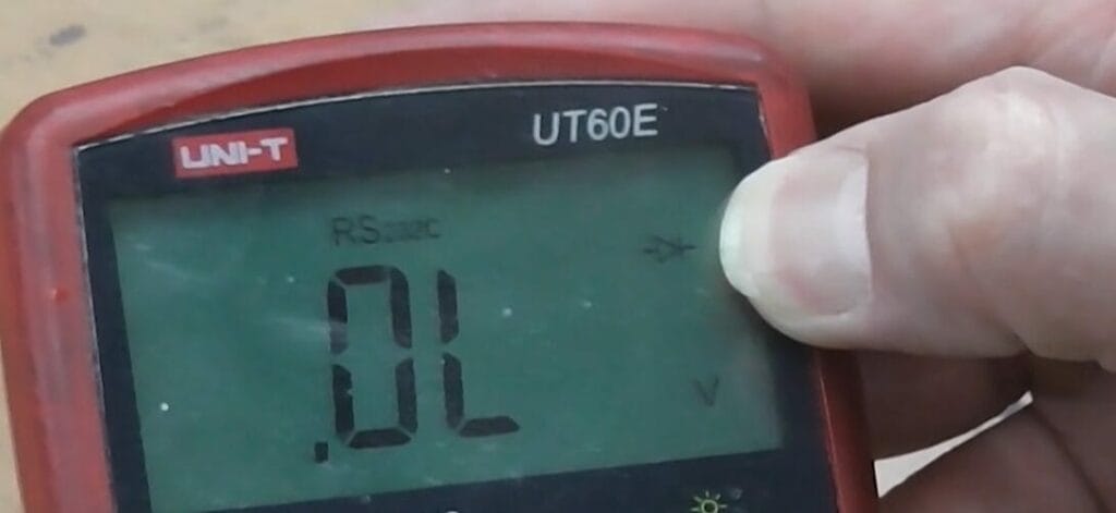 A man is holding a UNI-T UT60E red multimeter