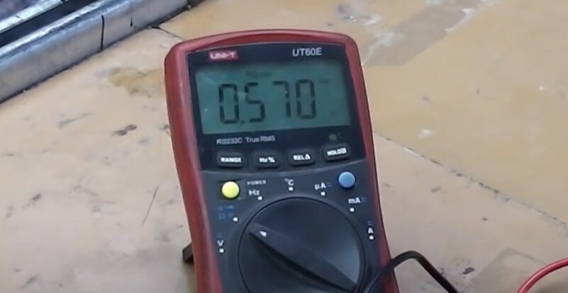 A digital multimeter on a table with 0.570 reading