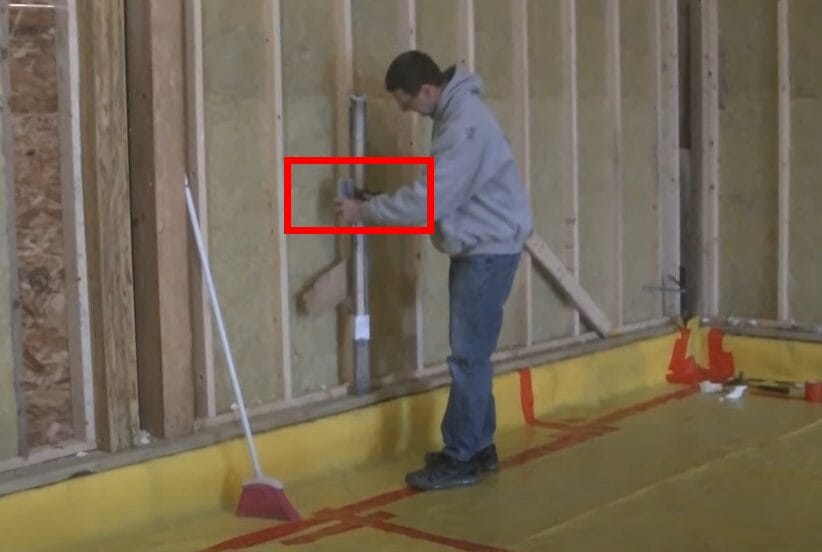 A man demonstrates how to use a laser level for grading in front of a wall