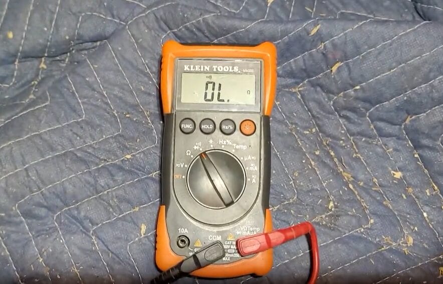 A multimeter is sitting on top of a bed