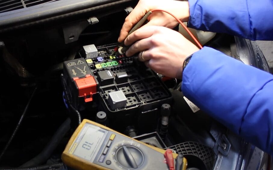A person testing car fuses with a multimeter