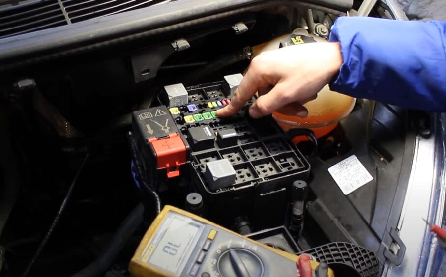 A mechanic with multimeter to test the car fuses