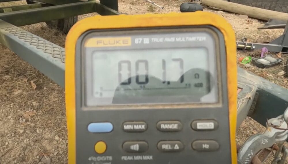 A digital multimeter on a trailer in the woods is used to test trailer brakes 