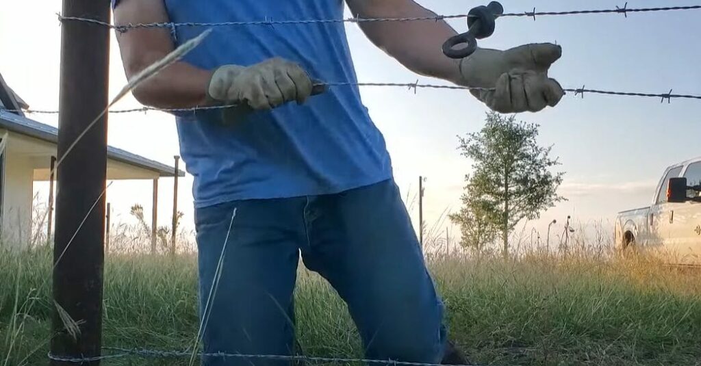 A man wearing gloves and installing a wire fence