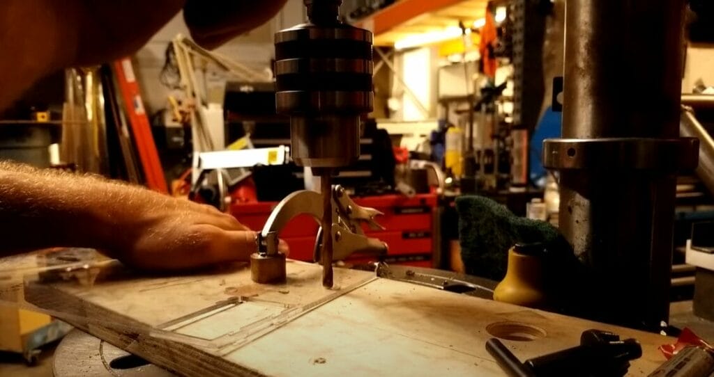 A man is working on a piece of wood, demonstrating how to drill a hole
