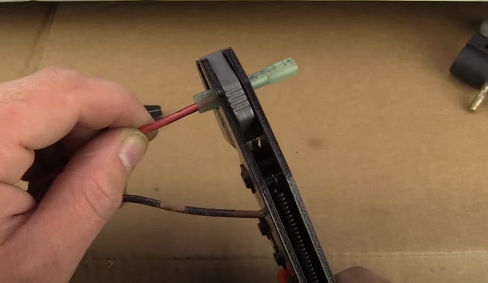 A person crimping the wire with crimping tool
