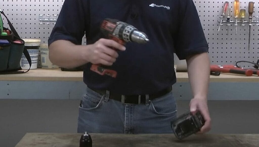 A man using a cordless drill in a workshop while demonstrating how to remove a milwaukee drill chuck