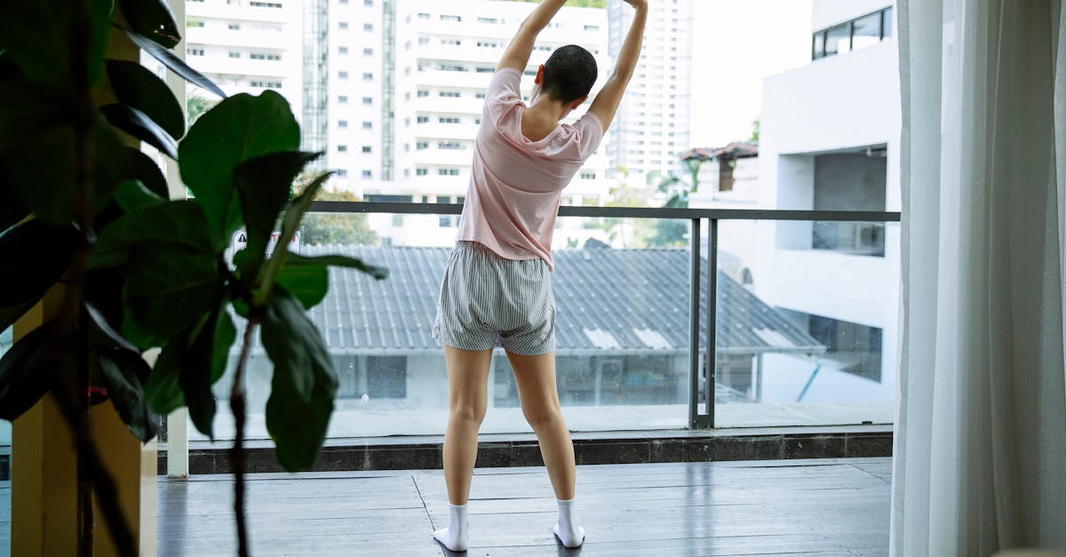 back view of anonymous female suffering from cancer stretching on glass balcony in hospital