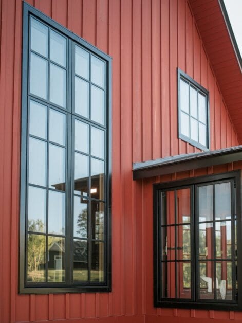 Close-up view of the Red Barn Retreat's exterior featuring large black-framed windows reflecting the stunning outdoor scenery.