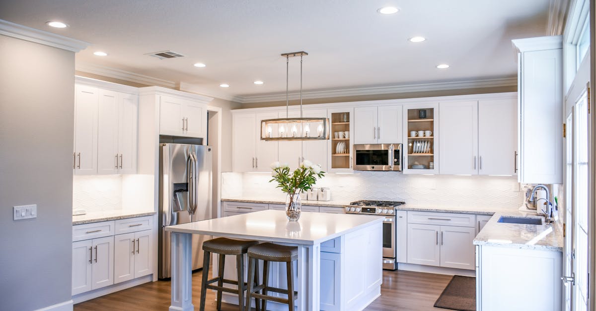 elegant white kitchen featuring an island modern appliances and ample natural light