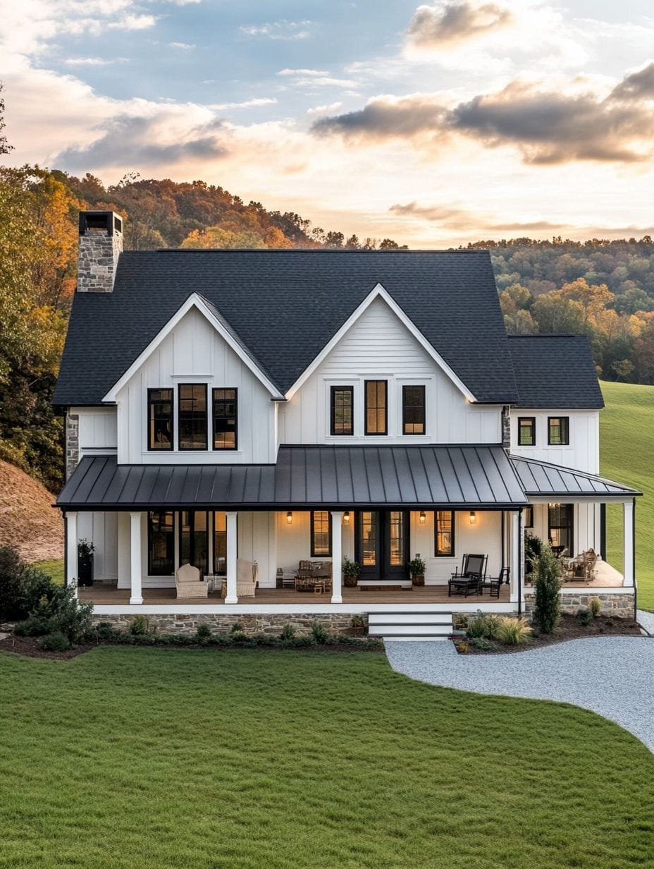 A two-story modern farmhouse with white siding, black roof, large covered front porch, and surrounding lawn, set against a backdrop of hills and trees at sunset.