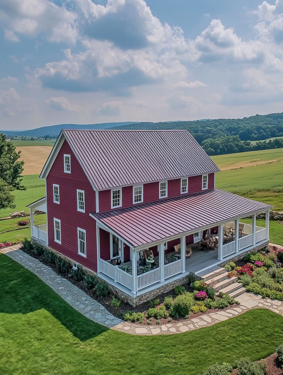A red two-story farmhouse with a large covered porch, surrounded by landscaped gardens and green fields under a partly cloudy sky.